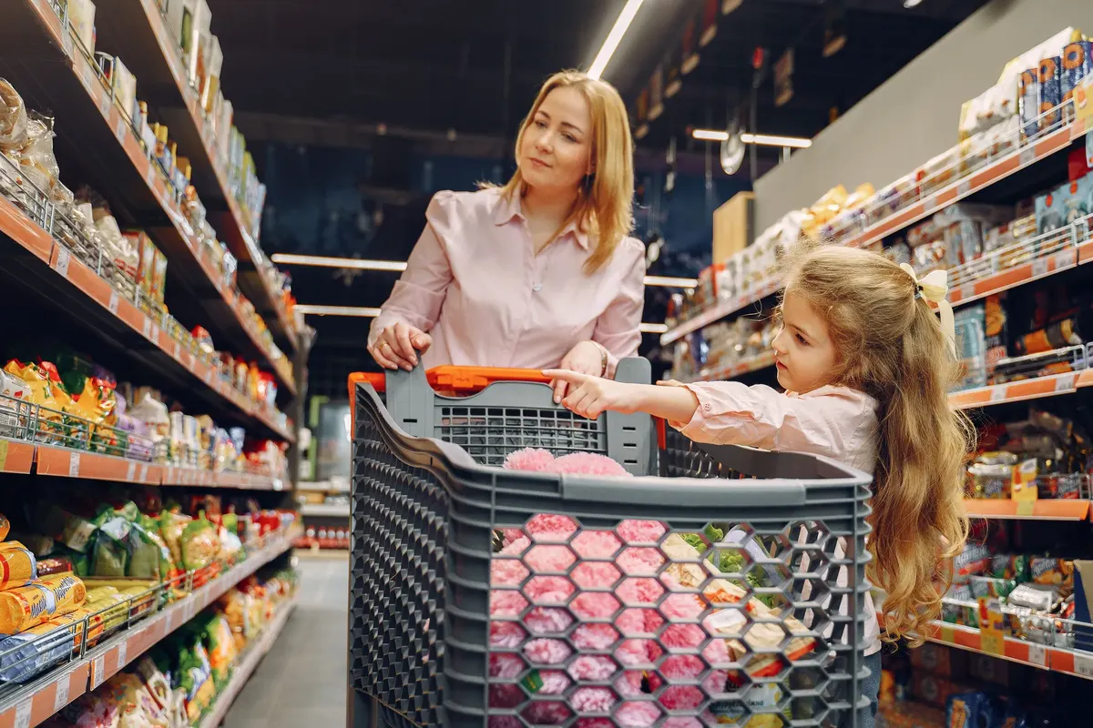 A mother and daughter choosing groceries in a supermarket aisle