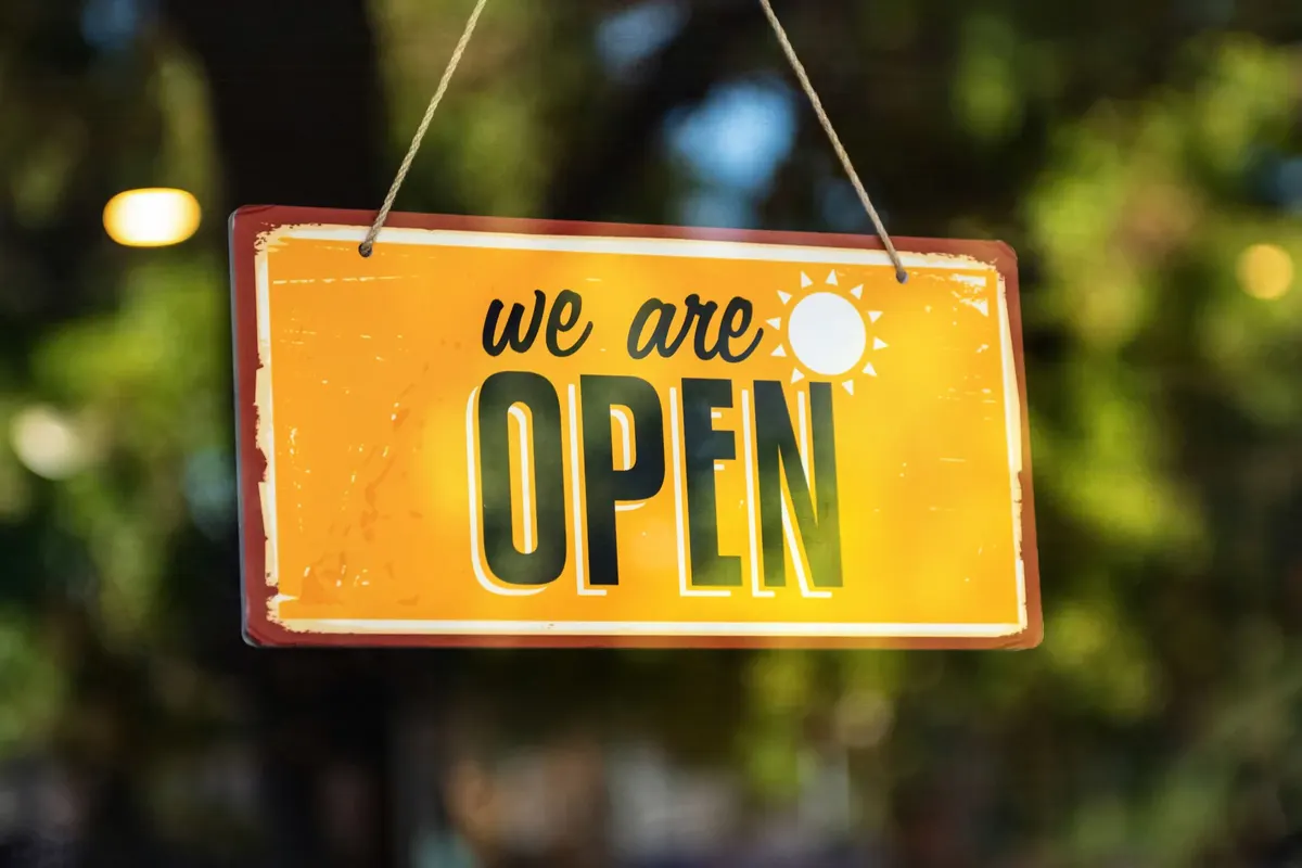 A yellow We are open sign on a shop door
