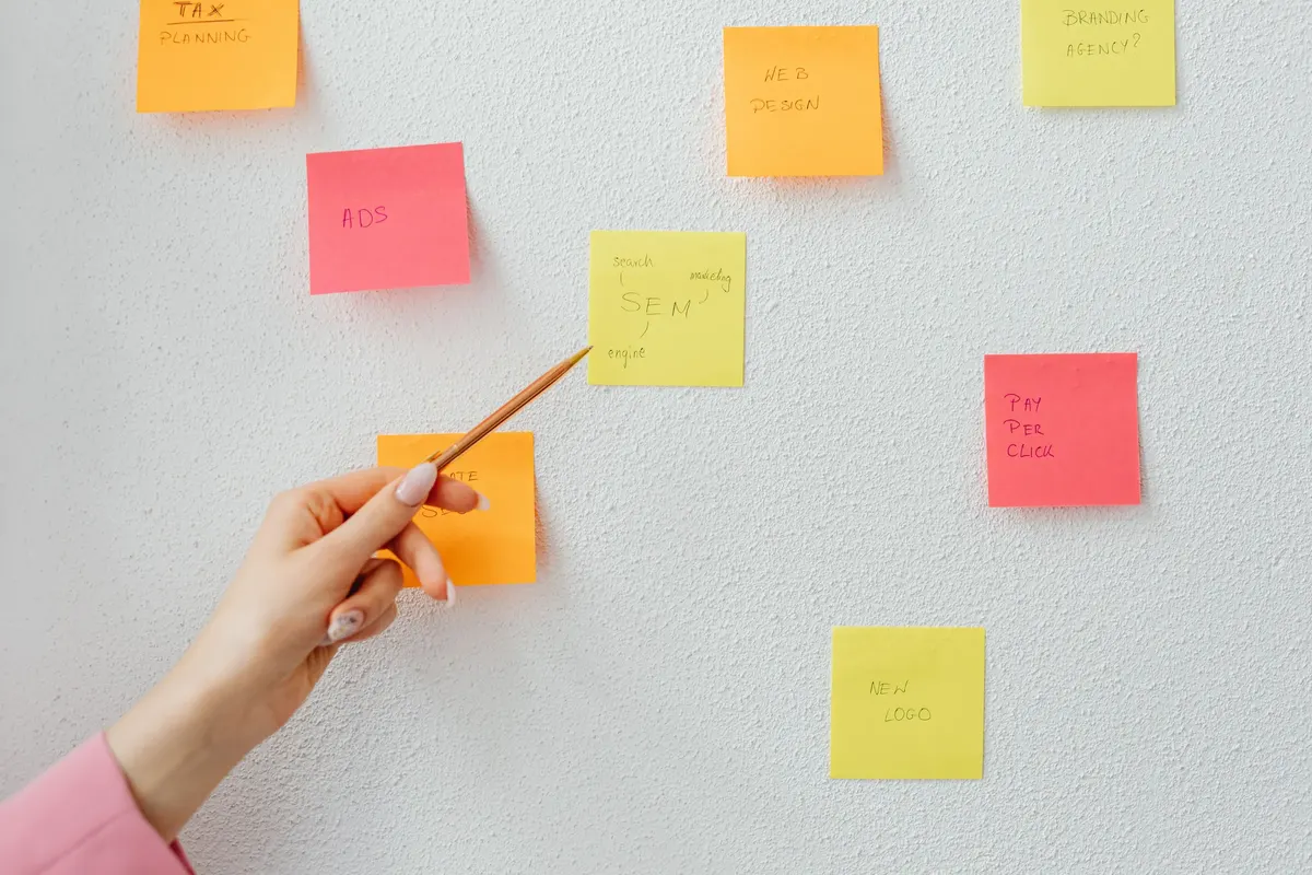 A hand pointing at sticky notes on a wall