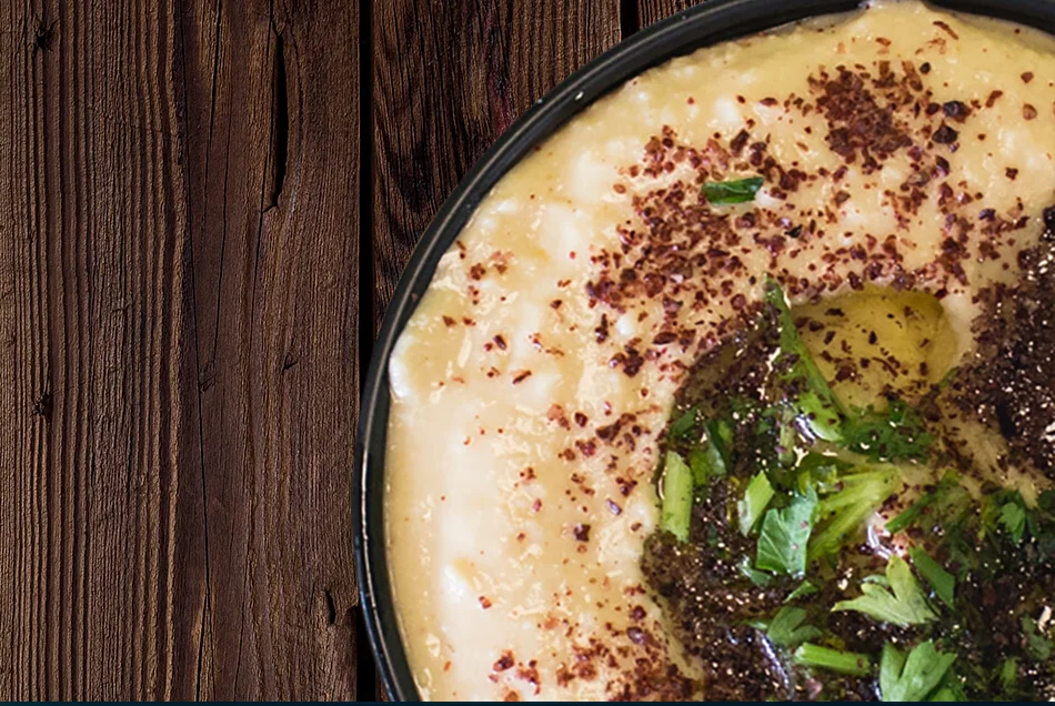 A bowl of hummus on a dark wooden table