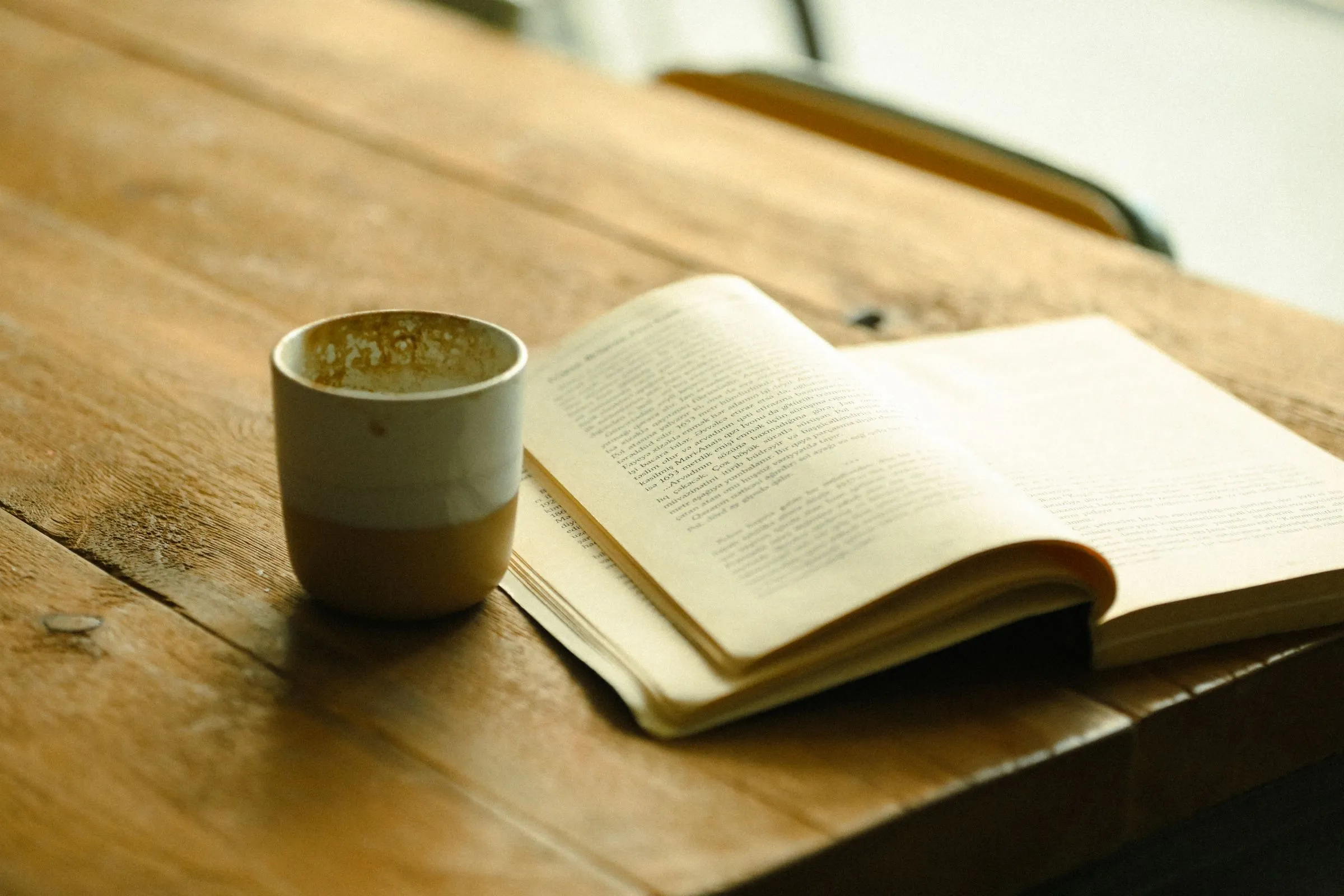An open book and a cup on a wooden table